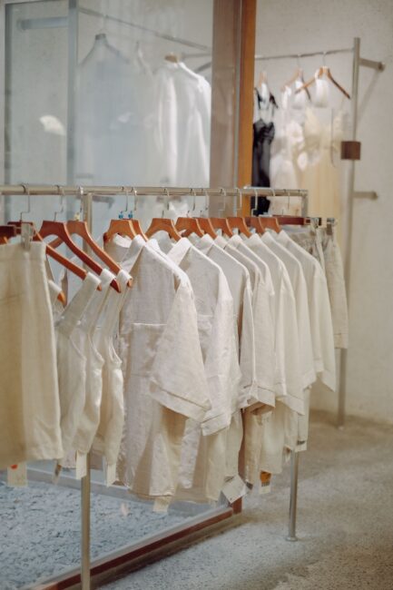 Araras com roupas organizadas por cor em uma loja de roupas